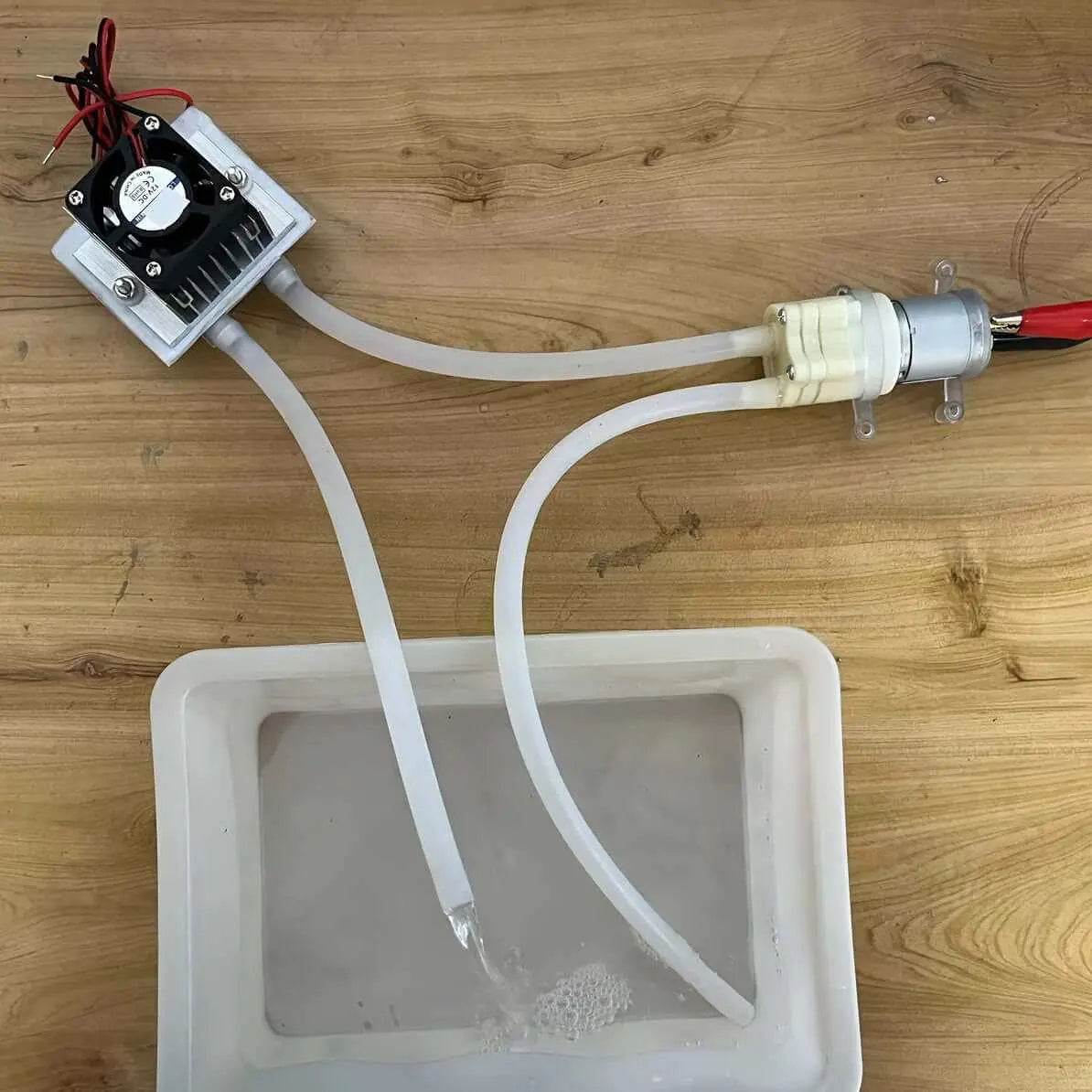 12V DC water cooling system kit showcasing diaphragm pump and cooling TEC1-12706 in use with tubing and water basin.