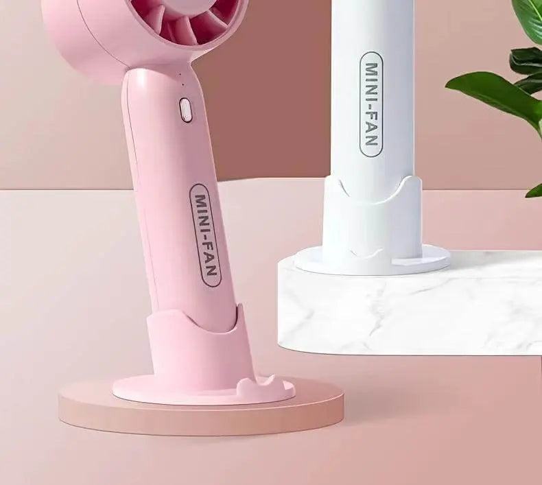 Portable mini fan in pink and white, featuring a USB rechargeable design with a polished finish, suitable for indoor and outdoor use.