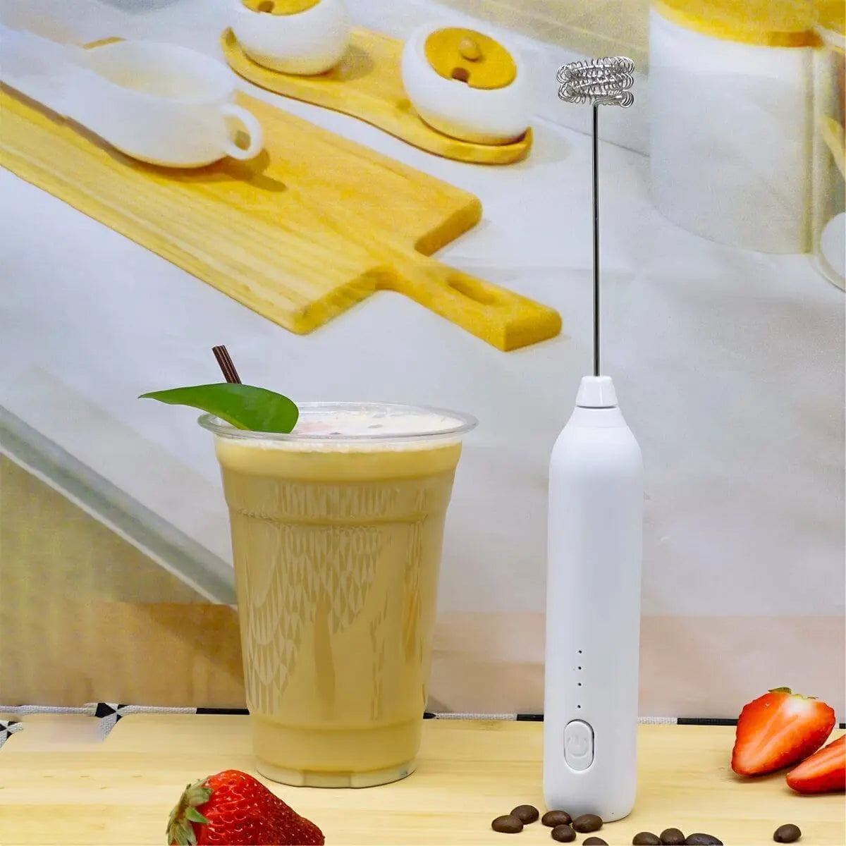 Portable handheld electric blender next to a glass of blended drink with strawberries and coffee beans.