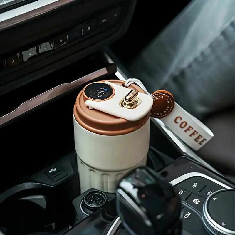 Stainless steel insulated coffee cup with digital display and matte finish in a car cup holder.